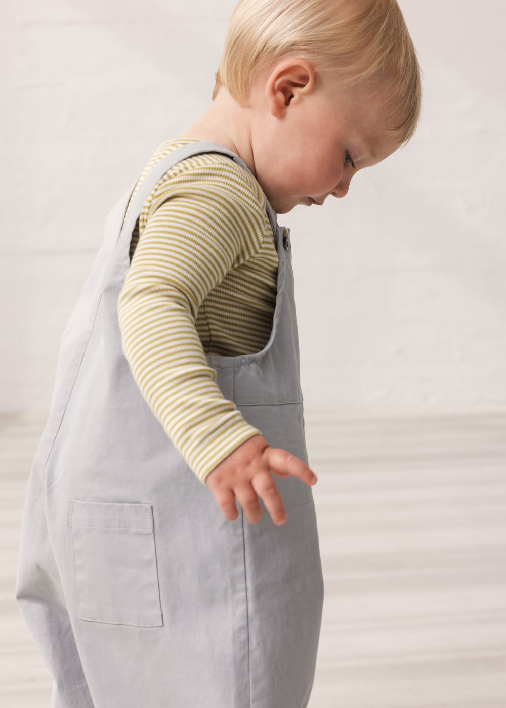 Children wearing green striped bodies under gray overalls.