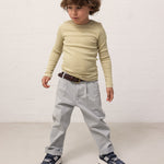 Child wearing a green-striped long-sleeved shirt and light blue chino pants.