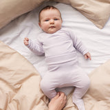Baby wearing a long-sleeved light lilac bodystocking and matching pants.