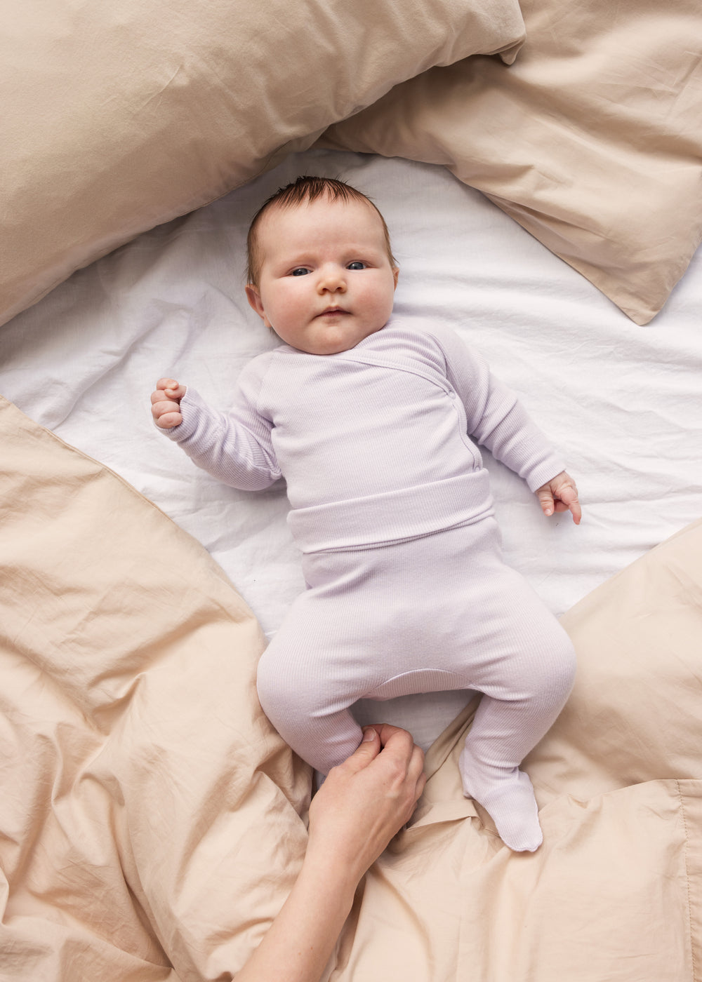 Baby wearing light purple pants with feet and matching body.