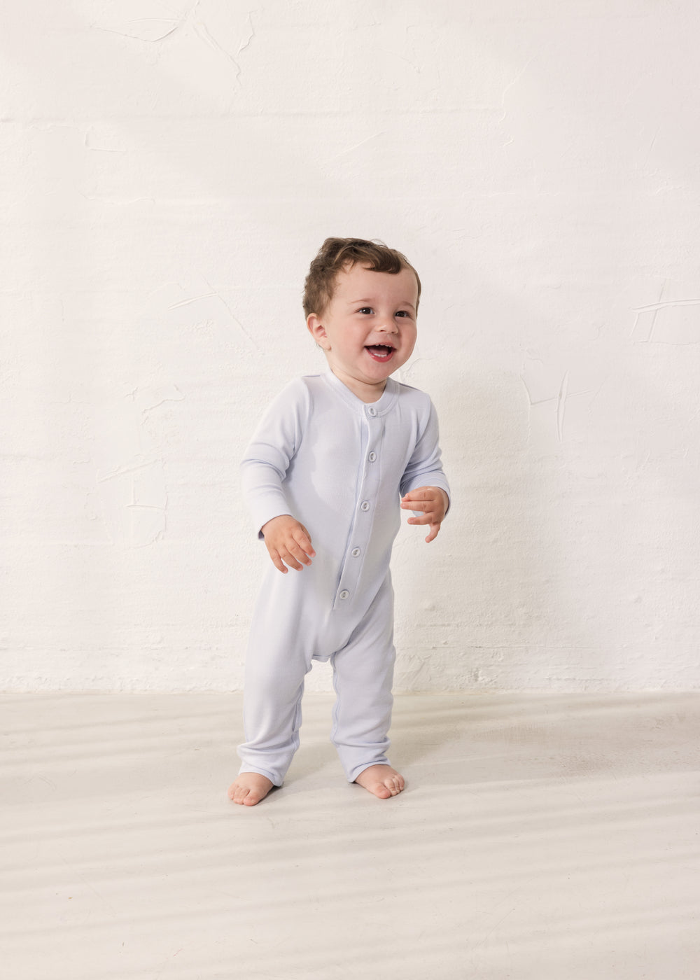 Baby wearing a light-colored dress with a long pole closure.