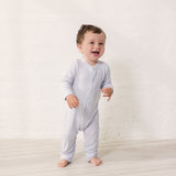 Baby wearing a light-colored dress with a long pole closure.