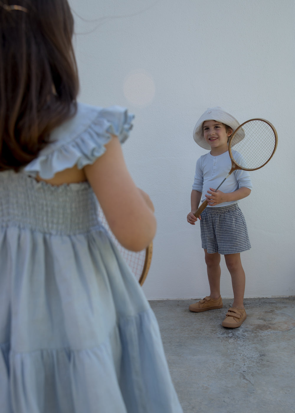 Child wearing a light dress and a hat with a mirror.