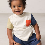 Baby wearing a raw white T-shirt with contrast sleeves and pocket.