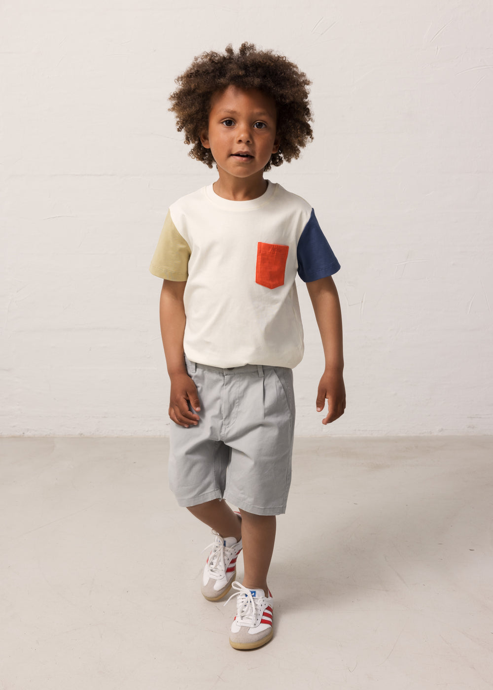 Children wearing a white T-shirt with contrast sleeves and a pocket.