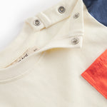 Short-sleeved baby T-shirt in raw white with contrasting sleeves and chest pocket.