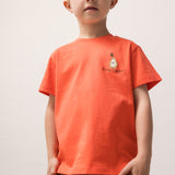 Child wearing an orange T-shirt and green shorts