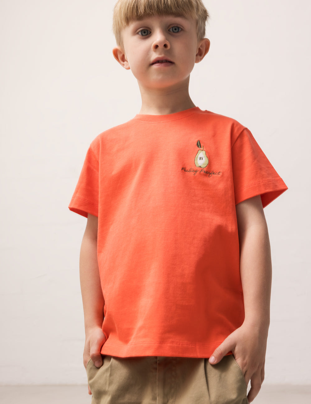 Child wearing an orange T-shirt with a small motif