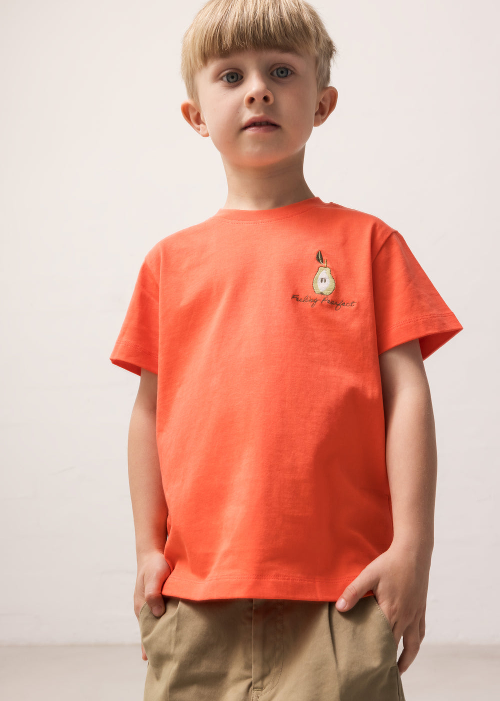 Child wearing an orange T-shirt with a small motif