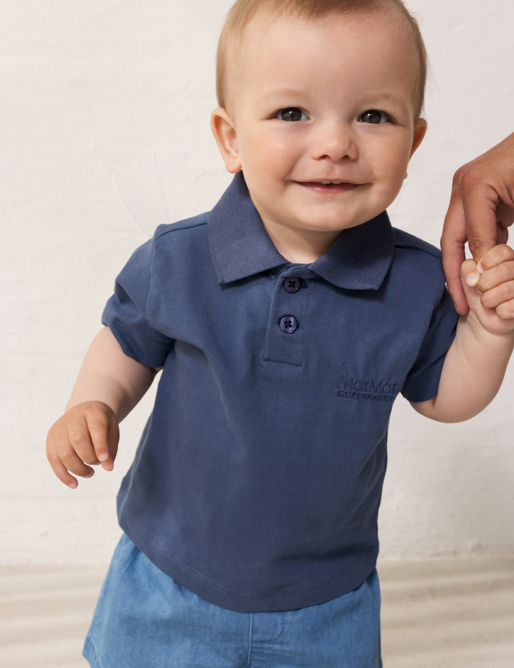 Baby wearing short-sleeved blue polo t-shirt with collar and button-up