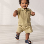 Baby wearing beige shorts and a matching top.