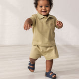 Baby wearing beige shorts and a matching top.