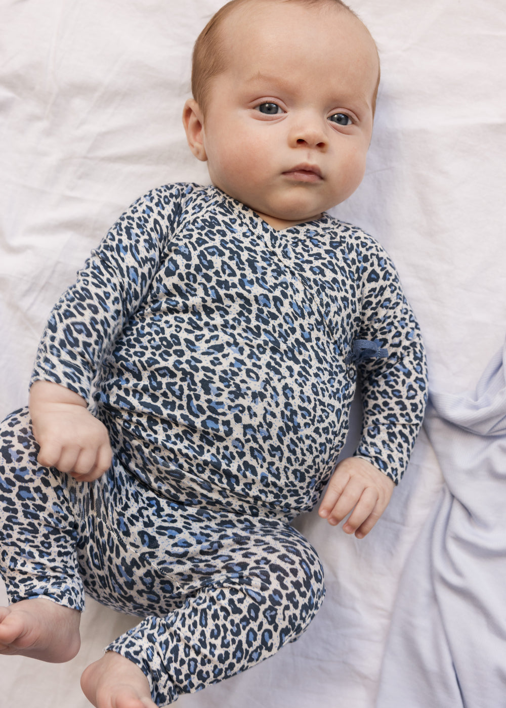 Baby wearing blue long-sleeved leopard bodystocking for newborns