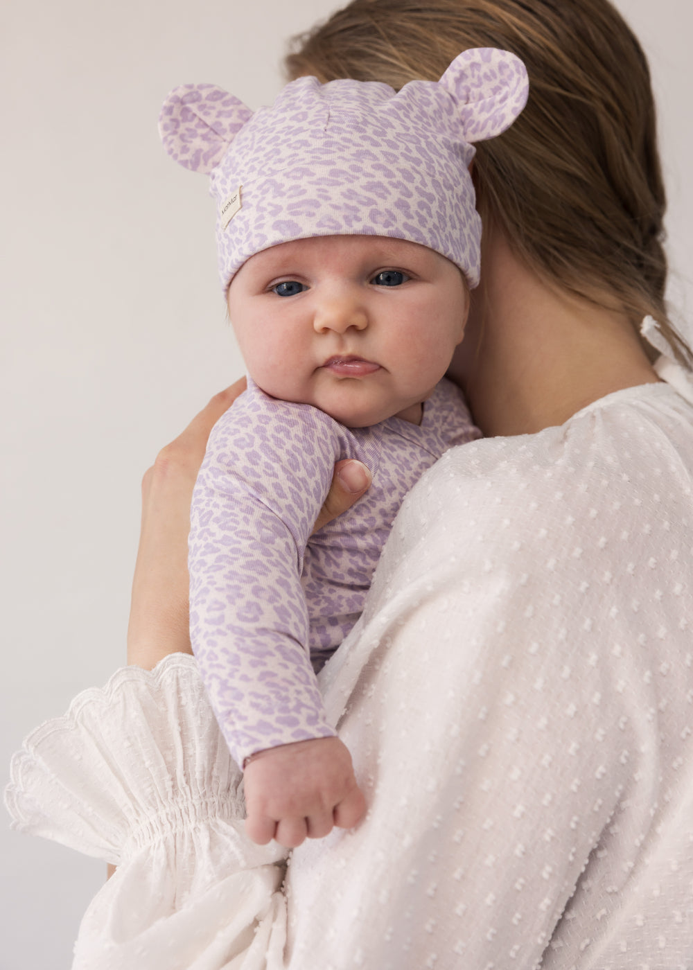 Baby wearing a knitted leopard hat with ears and matching outfit.