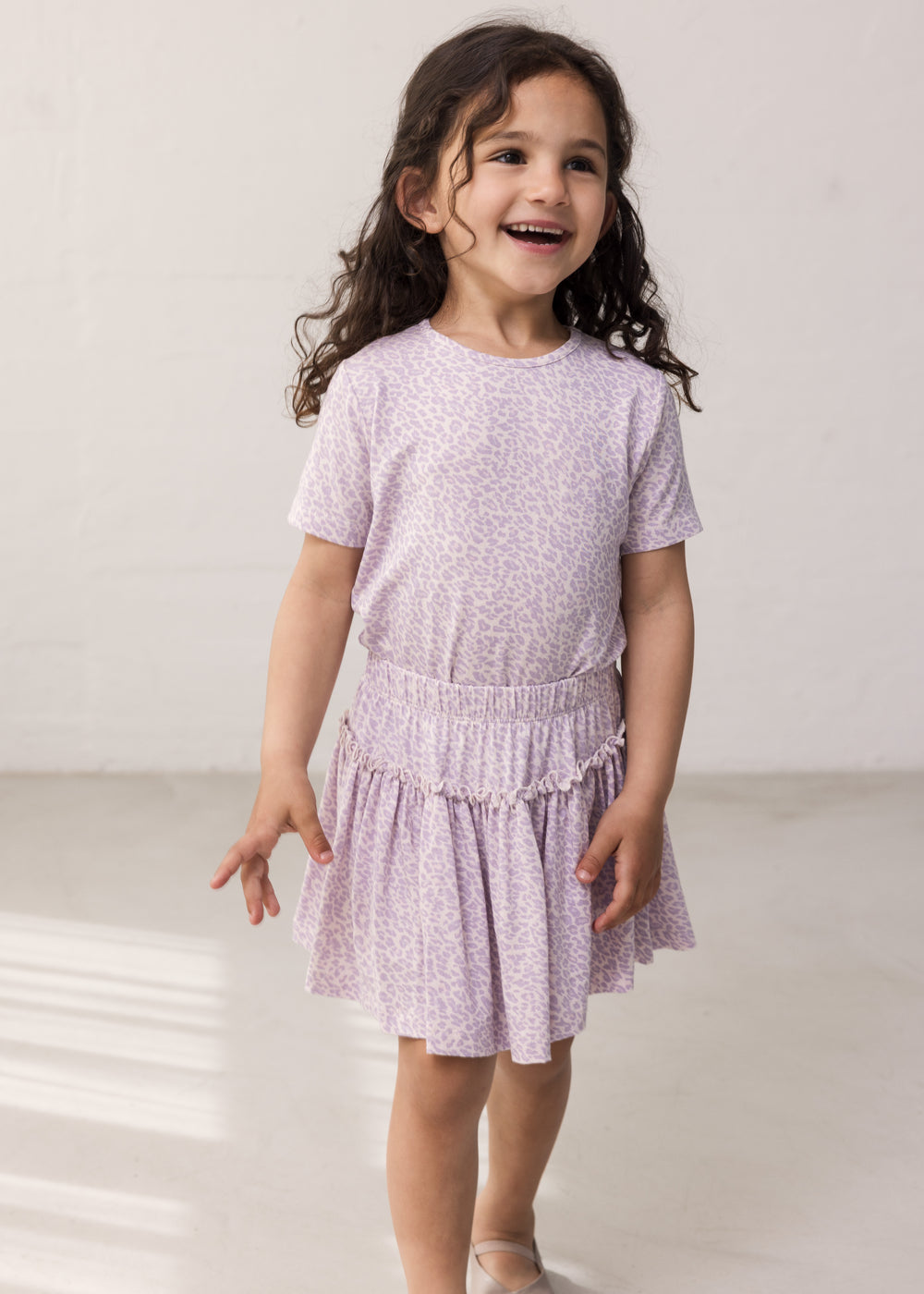 Child wearing a purple t-shirt and pants.