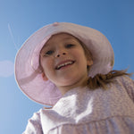 Wearing a bright yellow leopard print long-sleeved dress for children with elastic in the sleeves and a snap closure at the back, along with a matching sunhat.