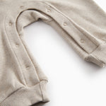 Beige baby onesie with ribbing on the neck, sleeves, and legs.