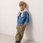 A child wearing a blue shirt and green pants.