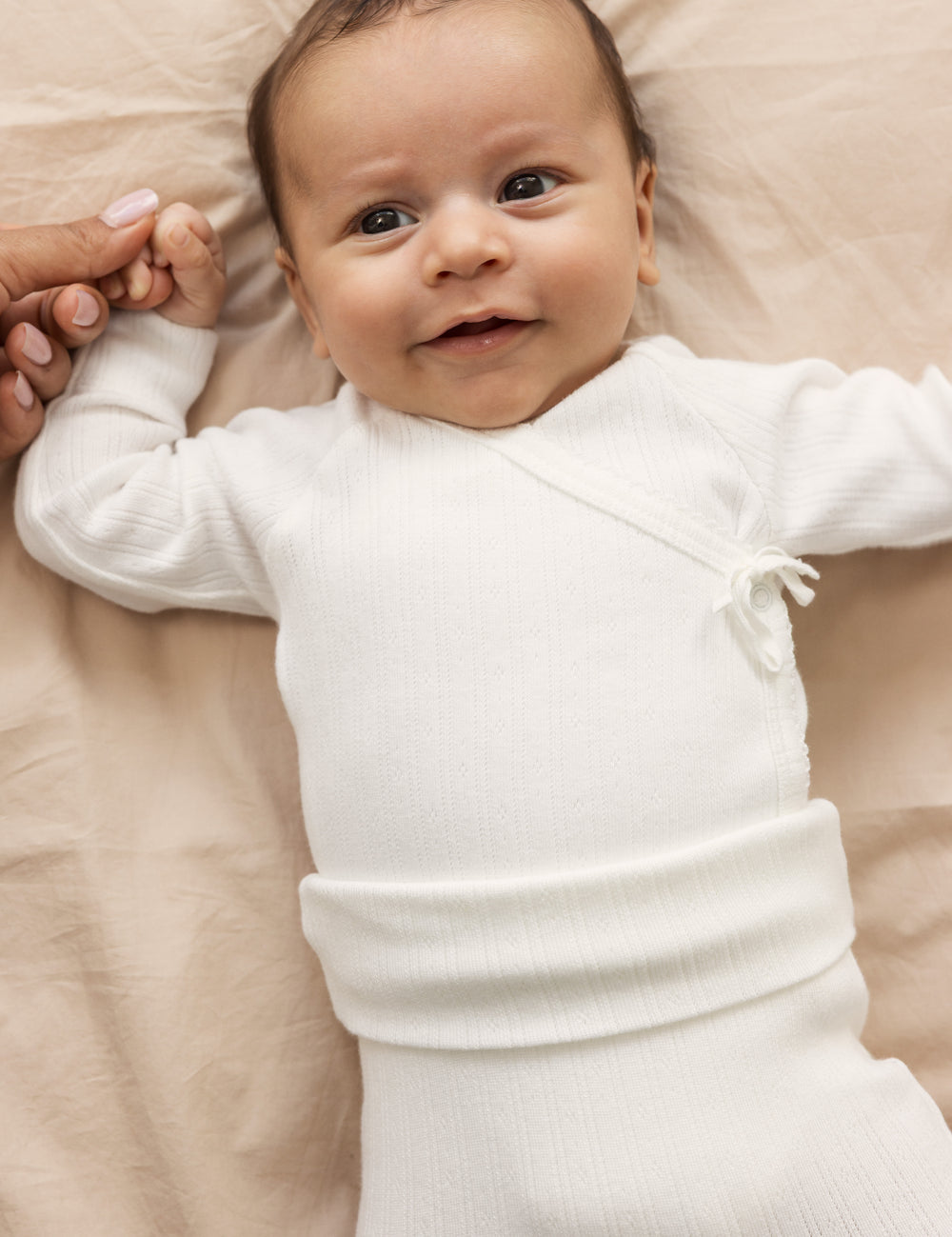 Baby iført råhvid body og bukser med elastisk talje