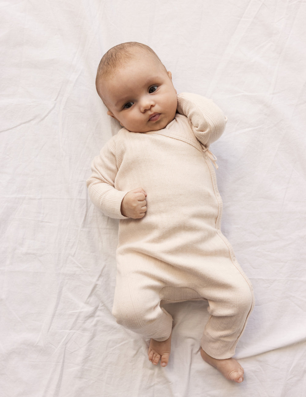 Baby wearing a long-sleeved, bright red pointelle cardigan with a front closure.