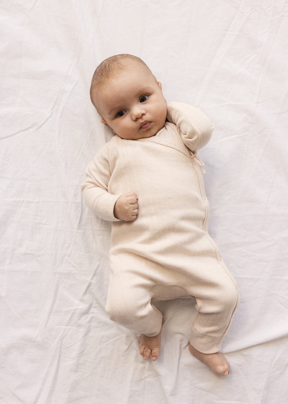 Baby wearing a long-sleeved, bright red pointelle cardigan with a front closure.
