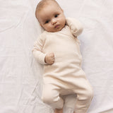 Baby wearing a long-sleeved, bright red pointelle cardigan with a front closure.