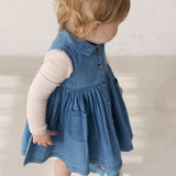 Child wearing a blue denim dress and long-sleeved body