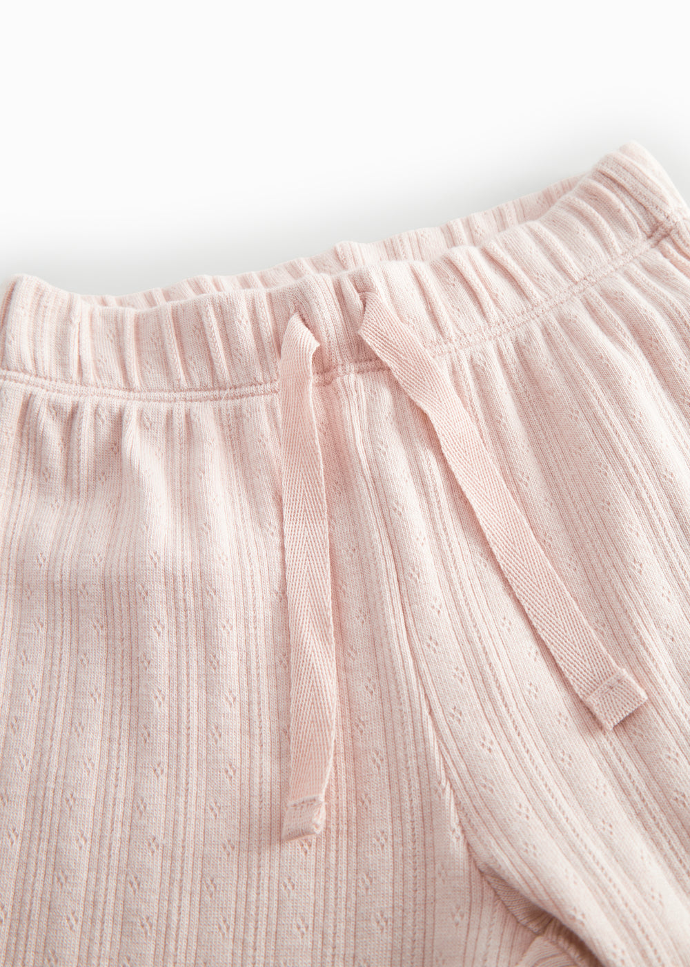 Red polka-dot baby pants with elastic and a decorative band at the waist.