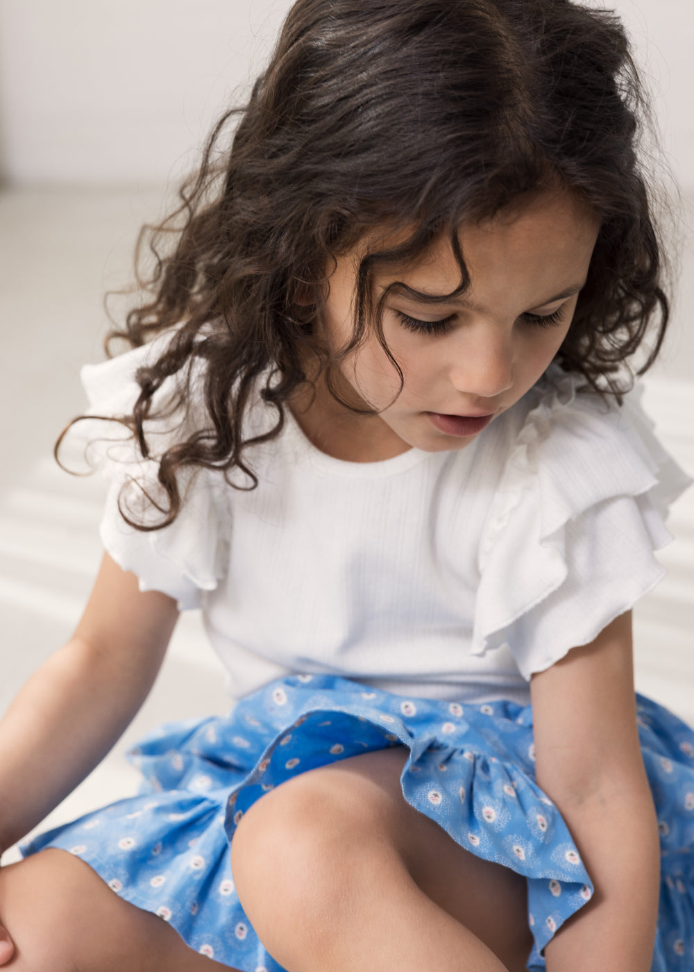 Worn short-sleeved white pique t-shirt with cuffs on the sleeves and blue floral bottom.