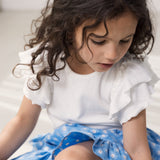 Worn short-sleeved white pique t-shirt with cuffs on the sleeves and blue floral bottom.