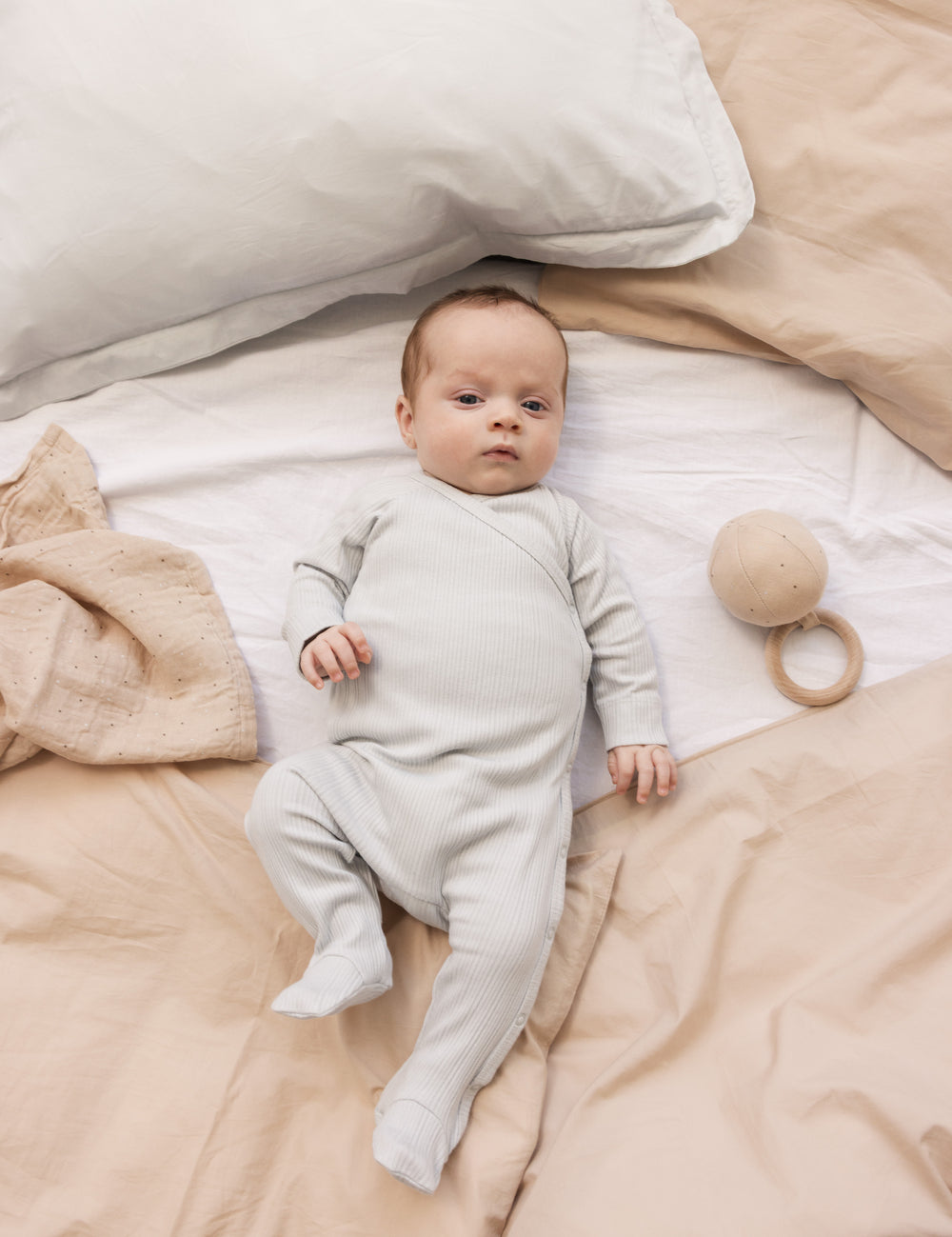 Baby wearing a long-sleeved light green pointelle held with feet