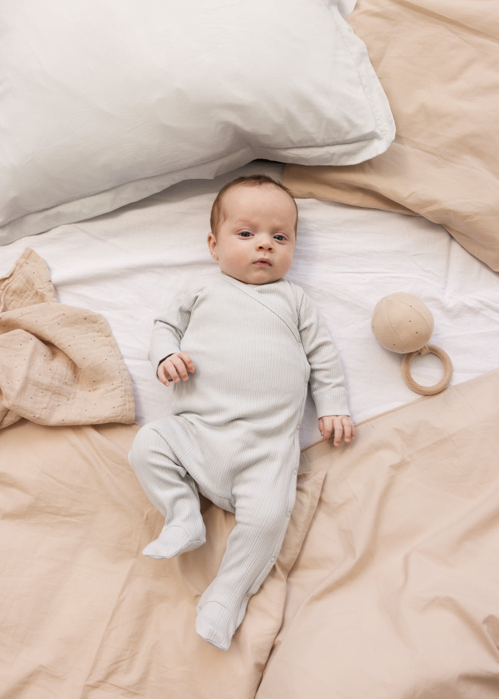 Baby wearing a long-sleeved light green pointelle held with feet