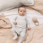 Baby wearing a long-sleeved light green pointelle held with feet