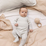 Baby wearing a long-sleeved light green pointelle held with feet