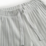 Green polka-dot baby pants with elastic and a decorative band at the waist.