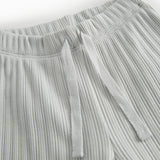 Green polka-dot baby pants with elastic and a decorative band at the waist.