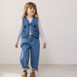 Child wearing a white t-shirt, blue denim vest, and matching pants.