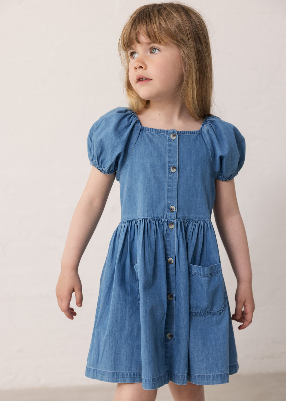Child wearing a blue dress with short puffed sleeves.