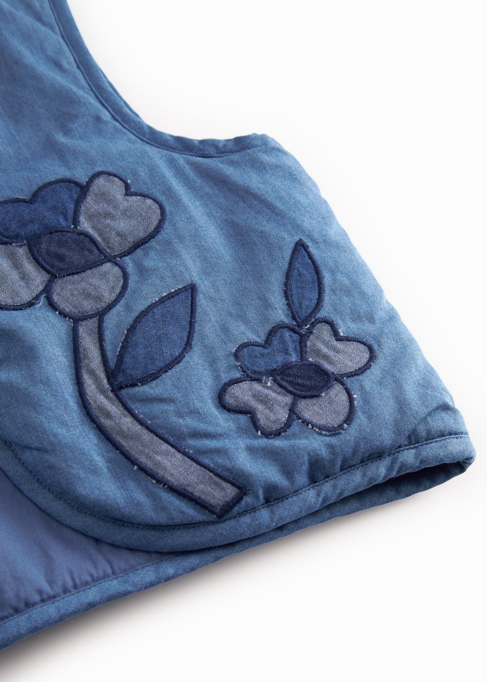 Blue denim vest for children with embroidered flowers.