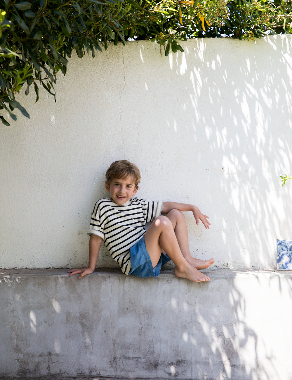 Child wearing a striped shirt and denim shorts.