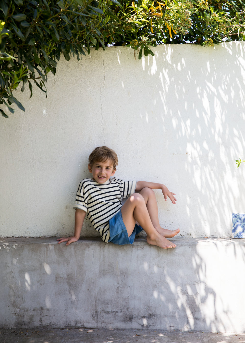 Child wearing a striped shirt and denim shorts.