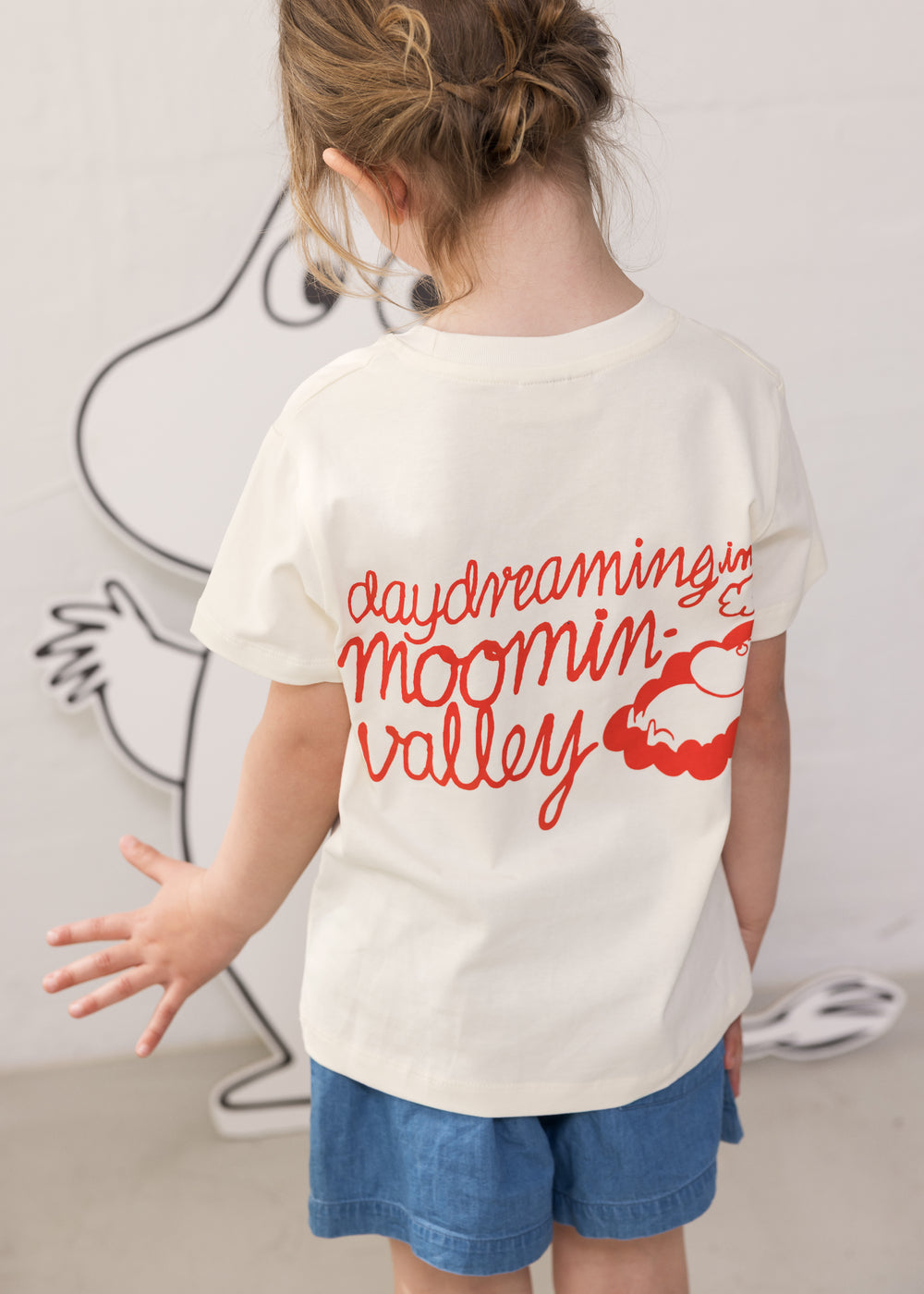 Children wearing Moomin T-shirts and blue denim shorts.