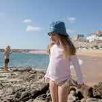 Child wearing a blue cap on a beach trip