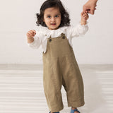 Baby wearing green chino shorts and a white blouse with ruffles.