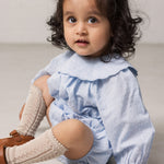 Baby pigeons wearing a light blue bodystocking with a delicate ruffled collar.