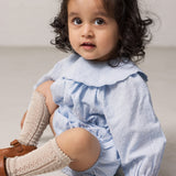 Baby pigeons wearing a light blue bodystocking with a delicate ruffled collar.