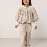 Children wearing a bright outfit with pants and a shirt.