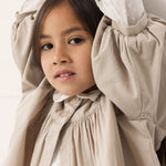Children wearing a light blouse with ruffle details.
