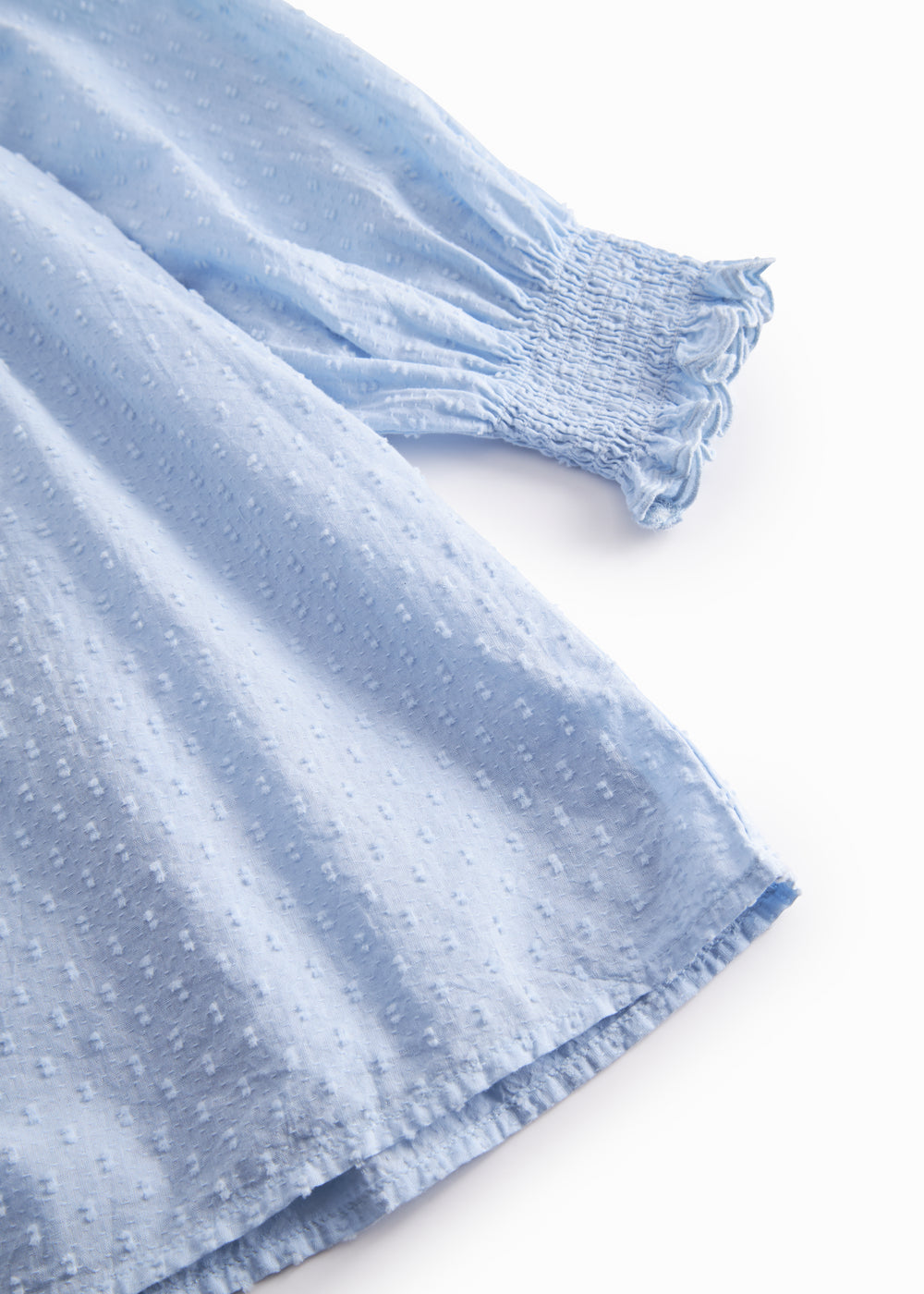 Langærmet lyseblå kjole med broderimønster, elastik ved håndleddene og rund halsudskæring med bølgede kanter