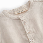 Sleeveless beige top for baby with ruffle details.